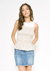 Woman wearing a white sleeveless top and denim skirt on a white background