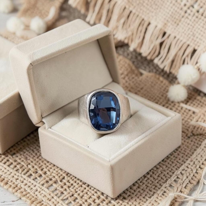Chandeliers Boutique ny blue crystal ring with silver plated brass band in a beige jewelry box on textured fabric.