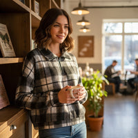 Woman wearing a Chandeliers Boutique ny black and white plaid crop flannel jacket with a half-zip collar in a cafe.