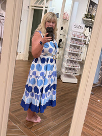 Woman wearing a Chandeliers Boutique ny cotton polka dot midi dress with a collared neckline and belted waist.