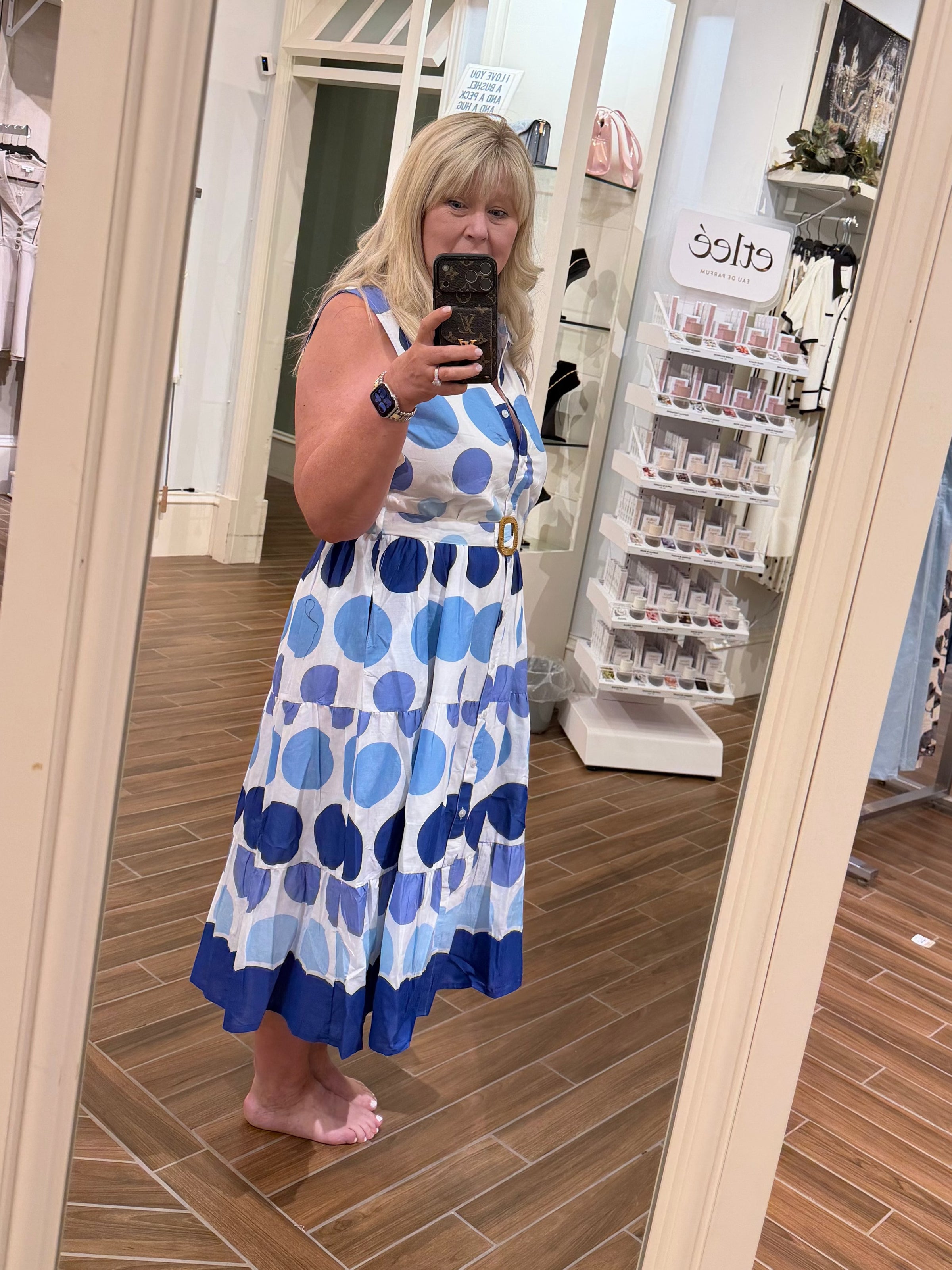 Woman wearing a Chandeliers Boutique ny cotton polka dot midi dress with a collared neckline and belted waist.