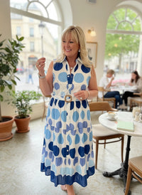 Woman wearing a Chandeliers Boutique ny sleeveless cotton midi dress with a blue and white polka dot print.